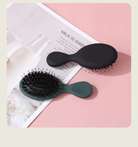 Mini boar bristle and nylon hairbrushes in black and dark green on a soft pink background