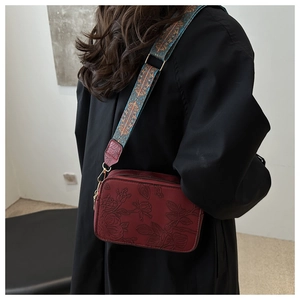 Close-up of deep red embossed leather bag with ethnic style wide shoulder strap