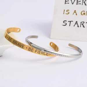 Detail of gold and silver stainless steel cuffs with engraved motivational slogans