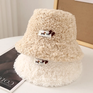 Cozy sherpa fleece bucket hats in beige and white with cute decorative patches and bows.