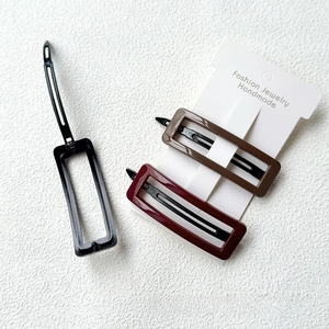 Detailed view of rectangular acrylic hair clips in black, brown, and red on display card