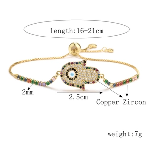 Detailed close-up of golden Hamsa Hand bracelet with colorful zircon evil eye charm