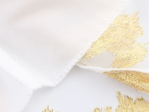 Détail du tissu texturé blanc élégant avec broderie dorée et couture de bord nette