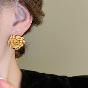 Macro di orecchini a fiore dorati con petali a spirale multistrato indossati dal modello