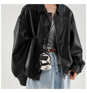 Detail of mini cow-print accessory bag with metal carabiner on a model leather jacket