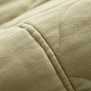 Vue macro du tissu sergé vert olive avec doubles coutures renforcées et texture matelassée