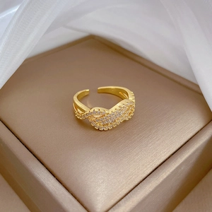 Detail of a gold adjustable crisscross ring with zircon inlay on a satin jewelry box