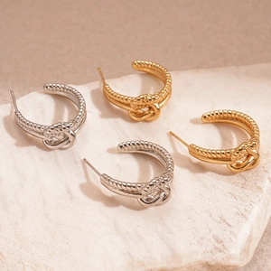 Boucles d'oreilles double C nouées en finitions or et argent sur pierre beige