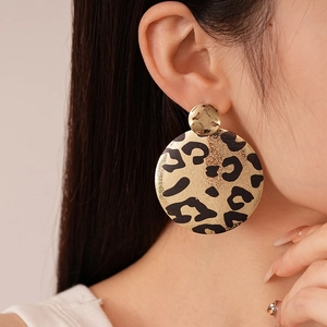 Boucles d'oreilles pendantes rondes dorées à motif léopard portées par un mannequin