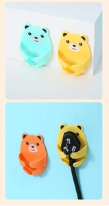 Detail of colorful bear-shaped wall hooks for power plug organization and cord management