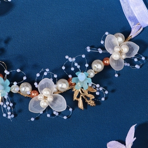 Handmade golden leaf and pearl bridal headband with blue flowers on dark background