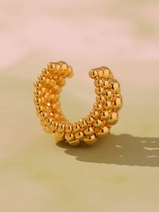 Macro shot of multi-layer golden bead chain ear cuff with polished metallic texture
