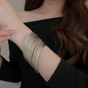 Close-up of stacked silver metallic bangles with a minimalist multi-layered design on a wrist