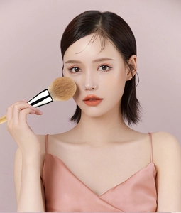 Close-up of soft powder brush bristles on skin with solid wood handle and silver ferrule