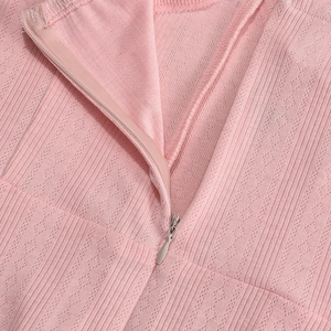Close-up of invisible zipper and pink ribbed fabric texture on the pleated dress