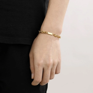 Close-up of gold titanium steel link bracelet with blank rectangular tag on wrist