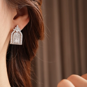 Close-up of geometric hollow silver earrings with zircon stones worn by a model