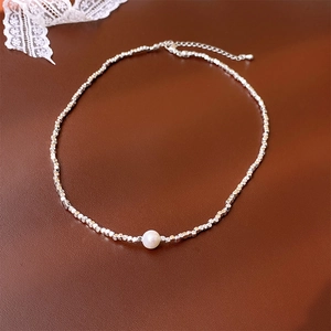 Vue macro d'un collier chaîne argentée avec perle blanche centrale sur cuir