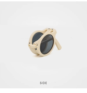 Side view of foldable kids round sunglasses in beige with grey lenses and compact design