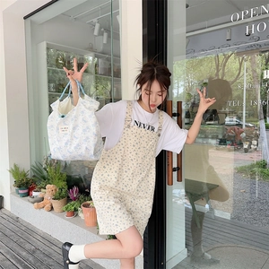 Detailed view of floral canvas tote bag paired with a casual summer outfit near shop storefront