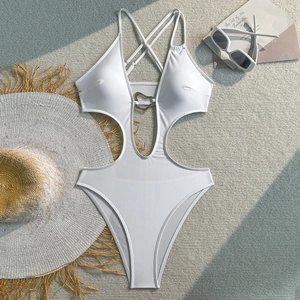 Flat lay of white cutout monokini with gold heart buckle and beach accessories