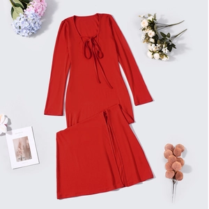 Flat lay of a red long-sleeve lace-up top and high slit skirt set on a grey background