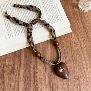 Dettaglio collana bohémien in tessuto leopardato con cuore in legno e ciondolo orb
