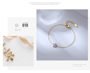 Close-up of golden steel bracelet with purple zircon flower and lobster clasp detail