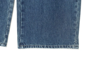 Macro shot of blue washed denim fabric with detailed stitching and texture on the hem