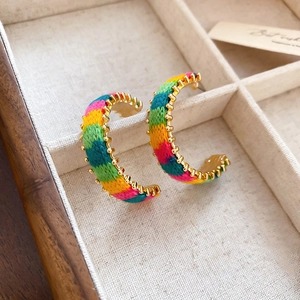 Macro detail of hand-woven C-shaped rainbow knit earrings with golden metallic beads