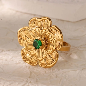 Dettaglio ravvicinato di un anello a fiore dorato con gemma verde su sfondo bianco