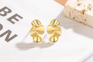 Macro view of gold irregular wavy earrings with polished metallic shell-like texture