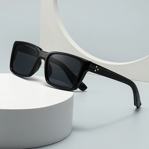 Vintage black square sunglasses with gold star accent on a white geometric display