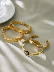 Detail of gold lion head medallion bracelet with hammered texture and chain link bangles