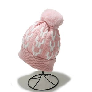 Detail of pink cable knit beanie with faux fur pom pom and thick ribbed cuff