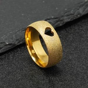 Detailed macro view of matte gold stainless steel ring with hollow heart-shaped cutout