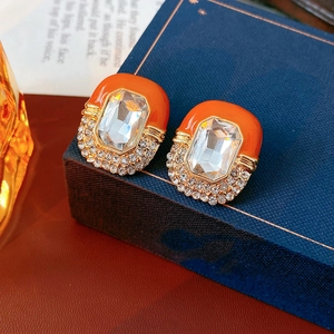 Macro shot of vintage gold earrings with orange enamel, rectangle crystal and small diamonds