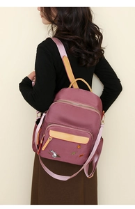 Detail of burgundy patchwork backpack with yellow straps and floral rabbit embroidery