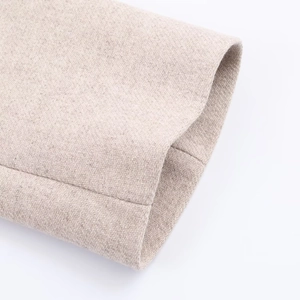 Dettaglio della manica del cappotto in lana beige con trama di tessuto saia di qualità