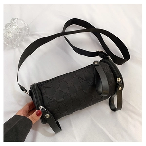 Detail view of black cylinder crossbody bag featuring textured fabric and fabric strap