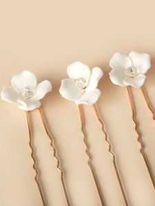 Detail of white ceramic flowers and crystal beads on golden wavy bridal hair pins