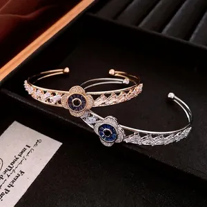 Elegant gold and silver open bangles with blue zircon flower design on a velvet base