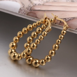 Macro detail of 23mm golden U-shape bead earrings showing smooth metal sphere texture
