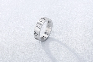 Macro shot of silver hollow Roman numerals engraved on a polished stainless steel ring band