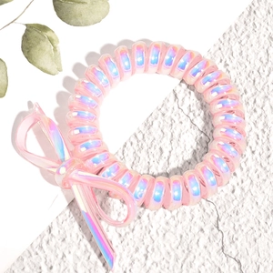 Gros plan d'un élastique spirale rose iridescent avec nœud décoratif sur fond blanc