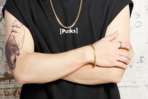 Gros plan d'un homme portant un collier et bracelet gourmette dorés avec bague argent