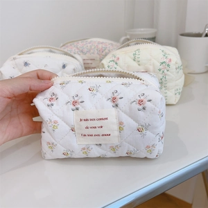 Détail de la trousse à maquillage en coton matelassé à fleurs avec fermeture éclair