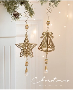 Close-up of golden hollow star and bell metal ornaments with crystal beads and tassels