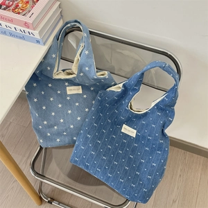 Détail d'un sac cabas en jean avec imprimé étoile blanche et écusson logo sur chaise