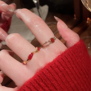 Detail of gold-plated rings with red enamel wave and disc designs on woman's finger